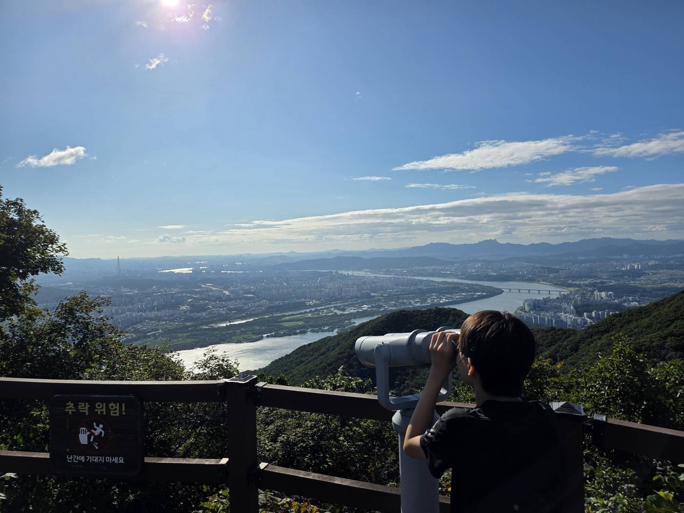 전망대 망원경으로 산 아래를 내려다보는 학생
